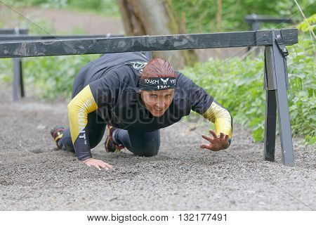 STOCKHOLM SWEDEN - MAY 14 2016: Struggling senior woman crawling under bars in the obstacle race Tough Viking Event in Sweden April 14 2016