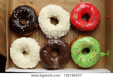 Six colorful donuts in a box, top view.
