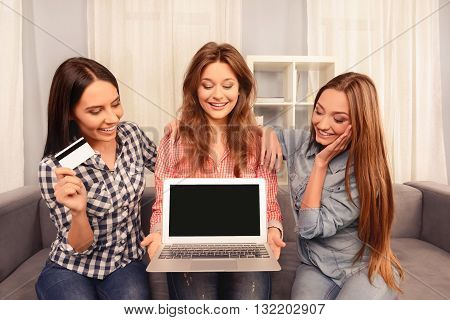 Three Pretty Girls Siting On Sofa With Laptop And Bank Card And Doing Shopping