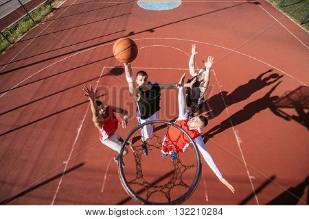 Team of basketball players playing basketball outdoors.