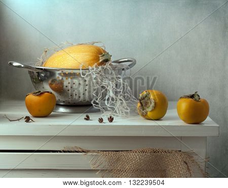 Still life with pumpkin and persimmon on wooden vintage table
