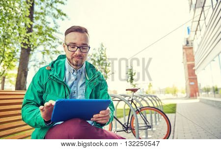 people, style, technology and lifestyle - happy young hipster man with tablet pc computer and fixie bike sitting on bench in city