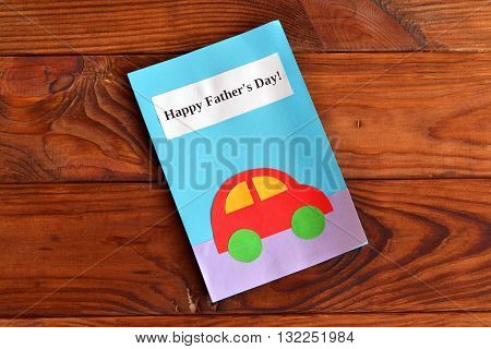 Greeting card with text Happy father's day and car applique. Greeting card on a wooden table. Father's day gift for kids to make. Original handmade gift. Home children paper diy