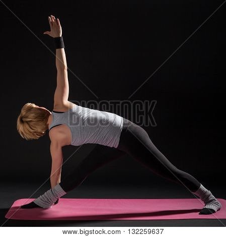 Young woman practicing yoga, Trikonasana / Bikram triangle left