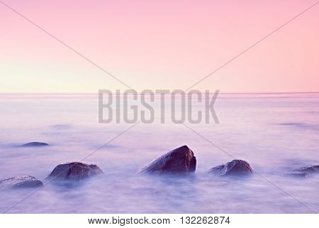 Romantic Morning At Sea. Big Boulders Sticking Out From Smooth Water Level. Pink Horozon With First