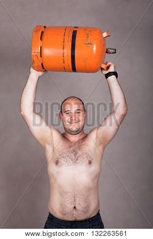 Portrait of happy strong shirtless worker man lifting heavy gas bottle.