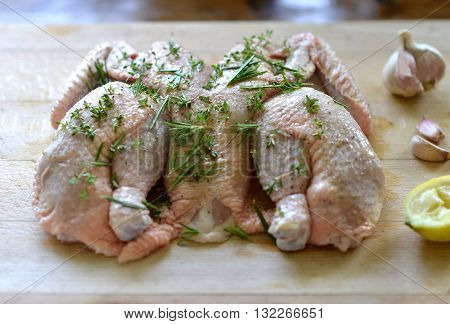 Raw spatchcock chicken with garlic herbs and lemon