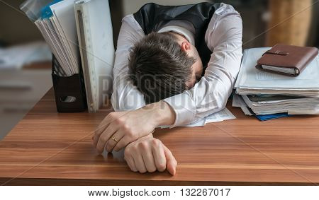 Tired Workaholic Is Sleeping On Desk In Office.