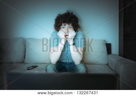 Man is watching thriller or horror on TV.