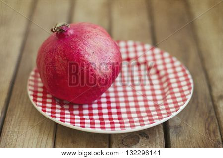 Red pomegranate on a plate over wooden table