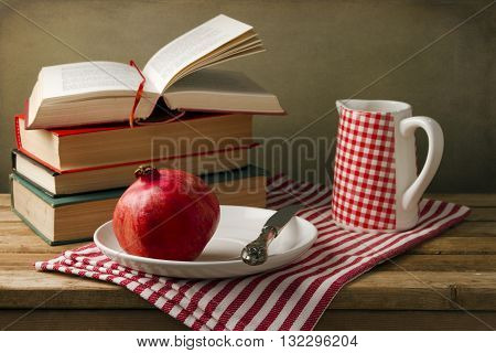 Still life with pomegranate on a plate and books