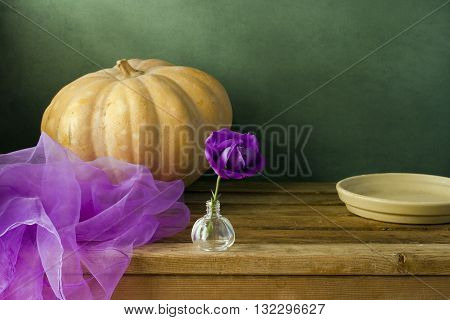 Pumpkin and purple flower on wooden table