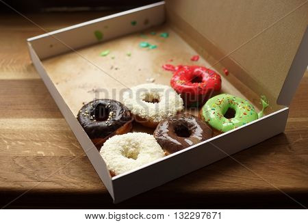 Colorful donuts in box, half-empty box, coconut topping