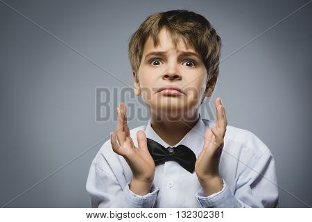 Closeup Portrait of handsome boy with astonished expression while standing against grey background.