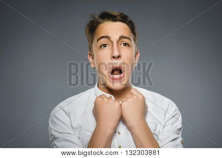 Closeup Portrait of handsome boy with astonished expression while standing against grey background.