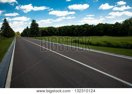 Bautiful road disappearing into horizon in middle of beautiful landscape with blue clouds. Beautiful road in deep green and yellow forest in wild.