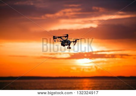 drone with remote control. Dark silhouette against colorfull sunset. Soft focus. Toned image