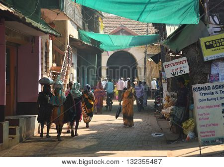 GOKARNA KARNATAKA INDIA - JANUARY 29 2016: Indian woman in yellow traditional indian sari walking down the crowded street in Gokarna city