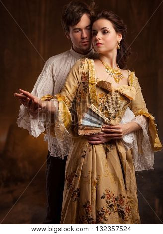 Lover couple. Man and woman standing on a stone wall background. Love relationship in a pair of man and woman. Images of the novel about love. Woman dreams. Man's instinct. Passionate, kissing, hugs.