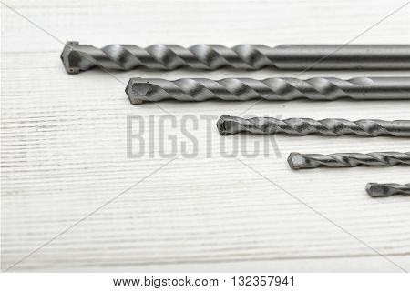 Different size drills posted from the highest to the lowest on a wooden surface. Construction instrument and tool. Set of drills. Mend and repair.