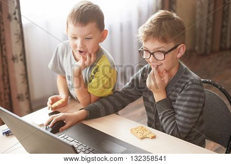 two boys play on a laptop boy t-shirt happy boy playing on a computer laptop, two brothers work there playing on the computer
