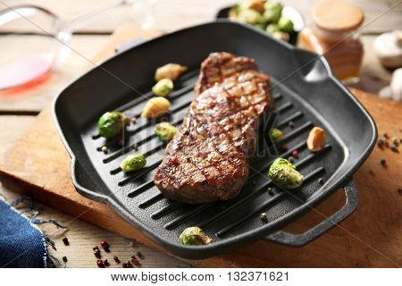 Grilled steak with garlic and Brussels sprouts on grill pan, closeup