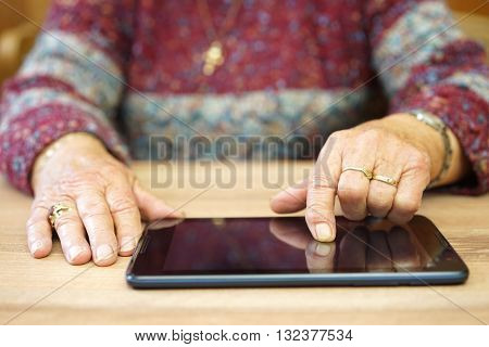 old woman is using tablet computer to surf on internet