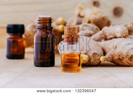 Bottles Of Ginger Oil And Ginger On Wooden Background With Selective Focus.