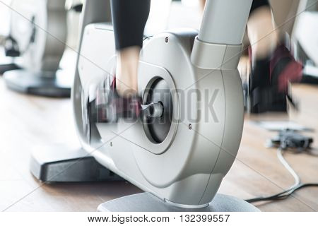 Detail of a woman working out on a stationary bike. Motion effect