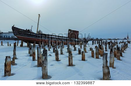 Old rusty ship on the winter shore of Lake Baikal.