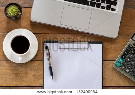 Office stuff with blank paper over blackboard pen calculator cup of coffee and labtop . Flat lay photo.Top view with copy space