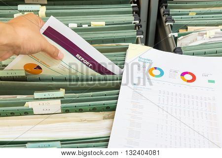 Hand holding report chart file in filing cabinet