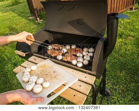 Red meat chops and champignons being placed on barbecue