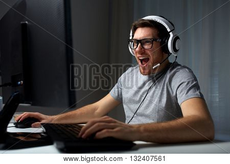 technology, gaming, entertainment, let's play and people concept - happy laughing young man in eyeglasses with headset playing computer game at home and streaming playthrough or walkthrough video