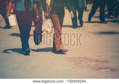 Retro toned image of pedestrians walking the street on a sunny day
