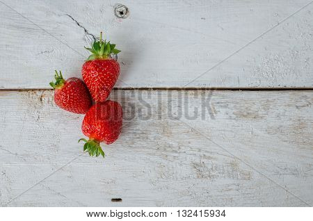 Red berry strawberry on white rustic wooden background. Background from freshly harvested strawberries with space for text. Strawberry background. Directly above. Top view. Copy space.