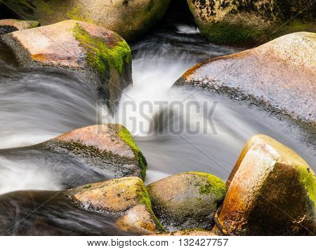Blurred river stream detail of wild rocky mountain river. Silky effect. Motion rendition effect. Slow shutter speed effect. Long exposure effect.