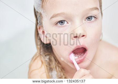 Dental hygiene. Close up of little girl brushing her teeth. Fun in the bath