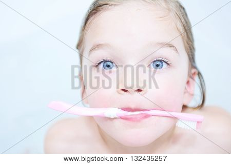 Dental hygiene. Close up of little girl brushing her teeth. Fun in the bath
