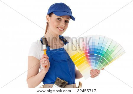 Young woman in  coverall with a color guide and paintbrushes on a white background.