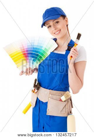 Young woman in  coverall with a color guide and paintbrushes on a white background.
