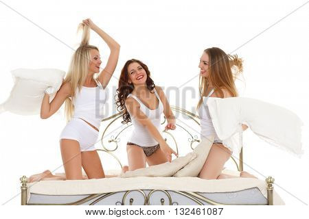 Happy cheerful girls having fun sitting on the bed on a white background. Pyjamas party.