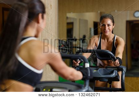 Beautiful sports woman exercising on the bicycle in the gym.