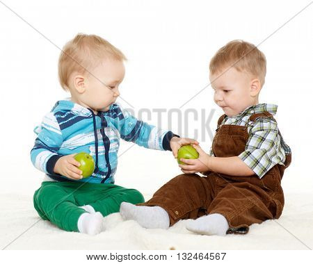 Two little boys with fresh apples sit on a white background. Healthy food.