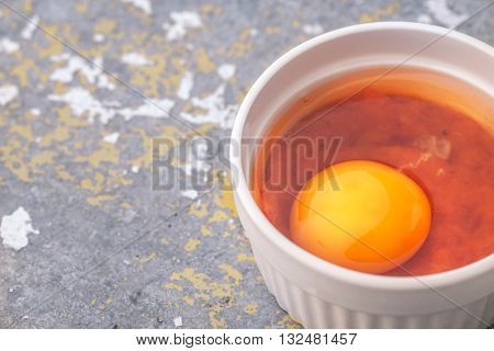 Raw eggs with tomatoes in the ramekins on the stone table
