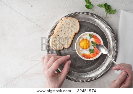 Eating eggs baked with tomatoes and parsley top view