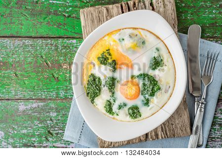 Florentine eggs with pureed spinach on the wooden table top view