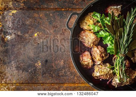 Boeuf Bourguignon with herbs in the pan on the metal background top view