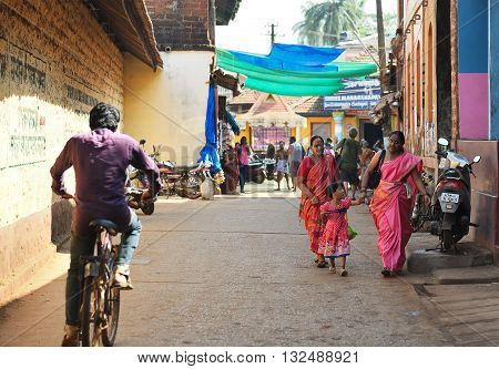 GOKARNA KARNATAKA INDIA - JANUARY 29 2016: Indian women with a girl wearing bright saris walking down in the street in Gokarna city