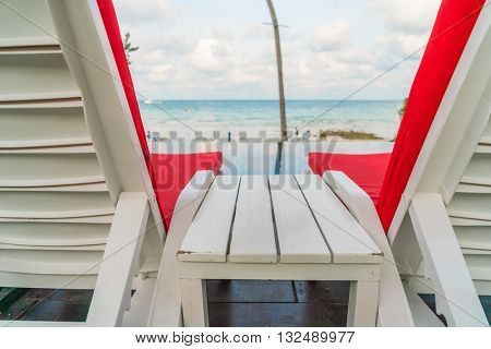 Beautiful beach chairs with umbrella around outdoor swimming pool neary sand and sea